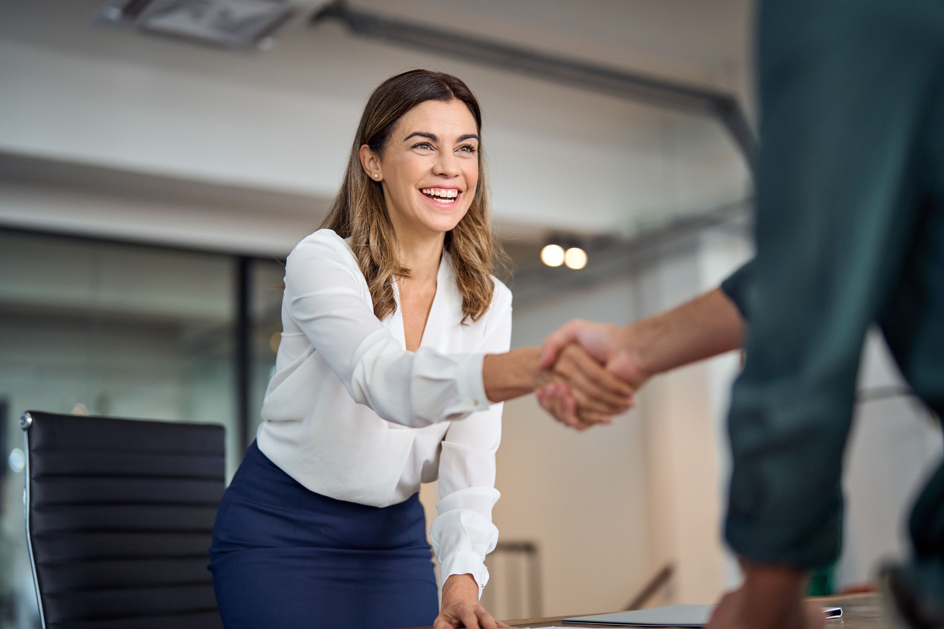 Felice donna d'affari di mezza età manager che stringe la mano salutando il cliente in ufficio.